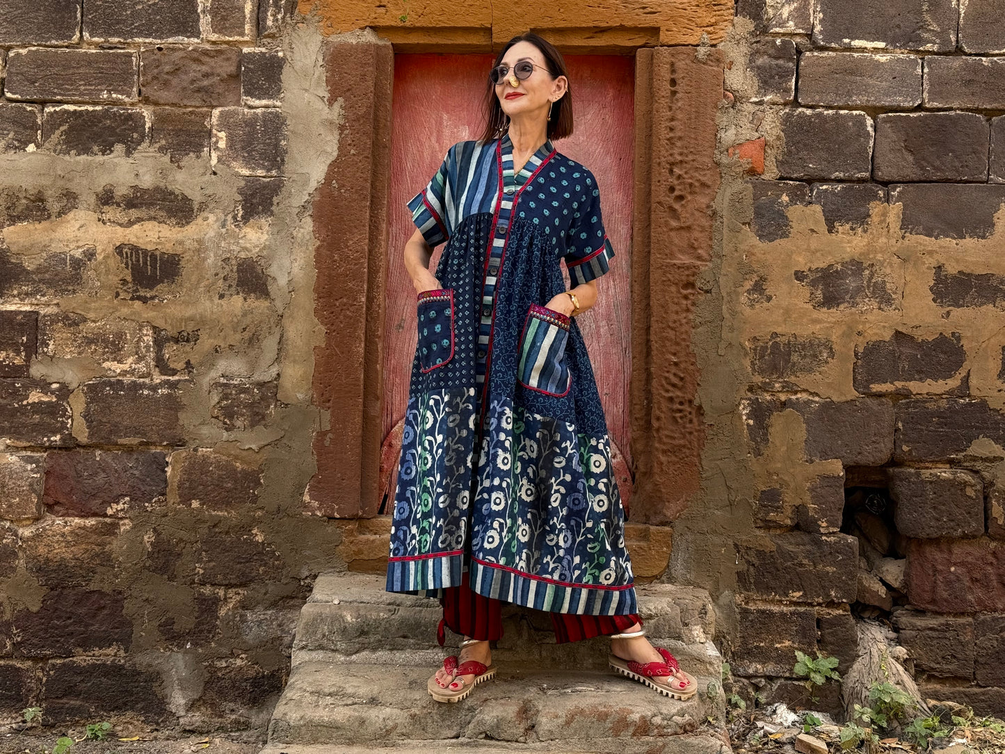 Button thru cotton dress in turquoise hues with red accents. All hand printed fabrics, this dress features vibrant Kutch hand embroidery.