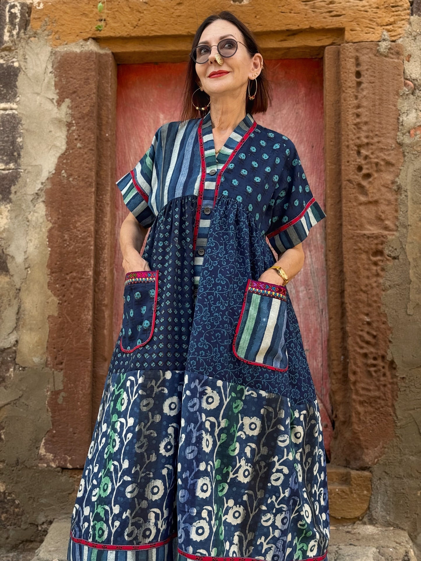 Button thru cotton dress in turquoise hues with red accents. All hand printed fabrics, this dress features vibrant Kutch hand embroidery.